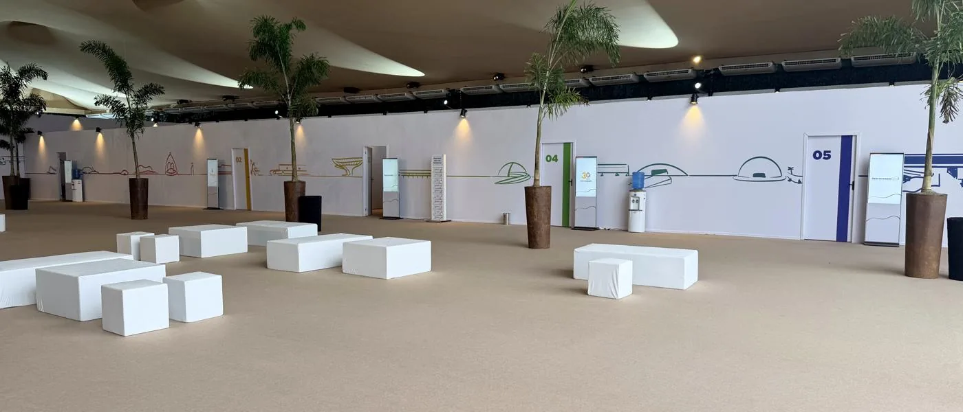 Salão de eventos com vários totens digitais distribuídos ao longo da parede